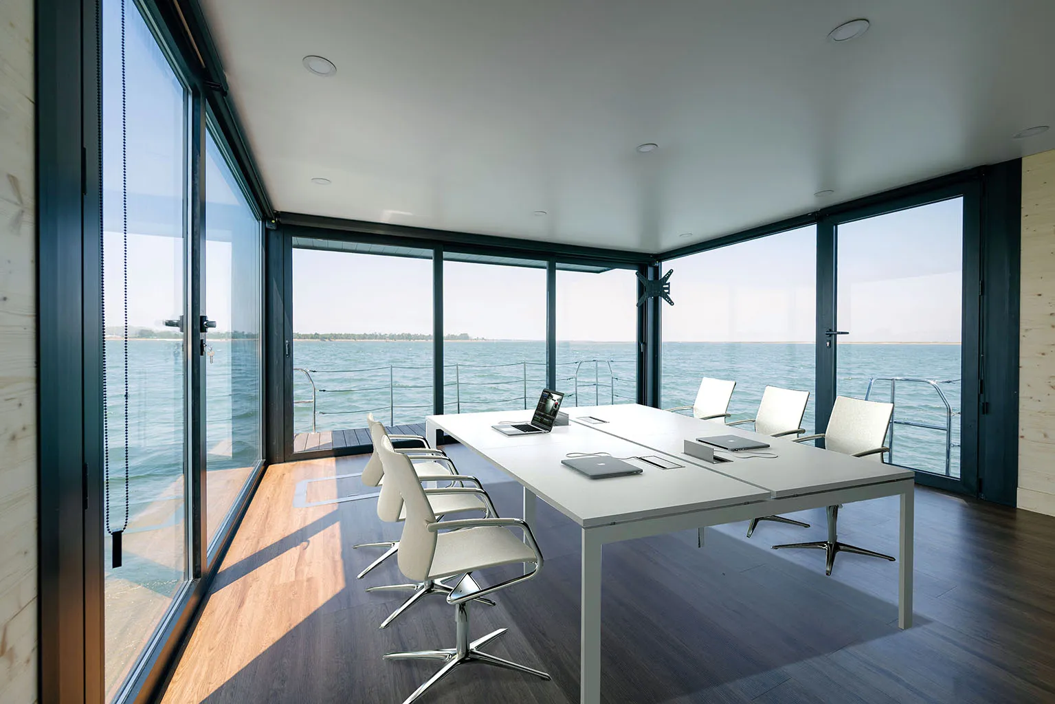 Floating office interior with meeting table, chairs and panoramic glass walls overlooking the water